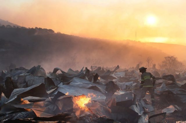 A firefighter removes the remains of a burned house on a hill, where more than 100 homes were burned due to forest fire but there have been no reports of death, local authorities said in Valparaiso, Chile January 2, 2017. REUTERS/Rodrigo Garrido