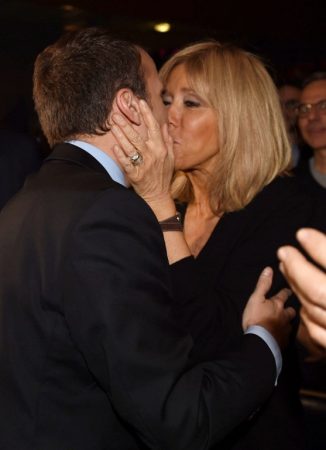 French presidential election candidate for the En Marche movement Emmanuel Macron kisses his wife, Brigitte Trogneux, as he arrives for a campaign rally on March 9, 2017 in Talence, southwest France. / AFP PHOTO / MEHDI FEDOUACH