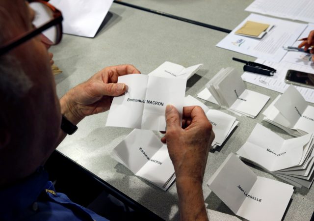 An official counts a ballot showing the name of Emmanuel Macron, head of the political movement En Marche !, or Onwards !, and candidate for the 2017 French presidential election, as the counting began for the first round of 2017 French presidential election, at a polling station in Tulle, central France, April 23, 2017. REUTERS/Regis Duvignau