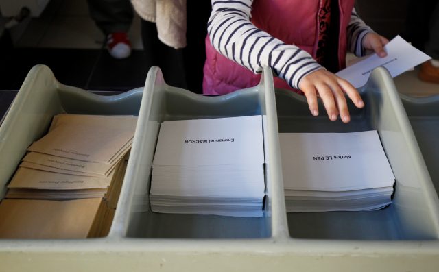 People pick ballots with the names of 2017 French presidential election candidates Emmanuel Macron  and Marine Le Pen as they wait before the opening of a polling station for the second round of 2017 French presidential election in Marseille, France, May 7, 2017.  REUTERS/Philippe Laurenson