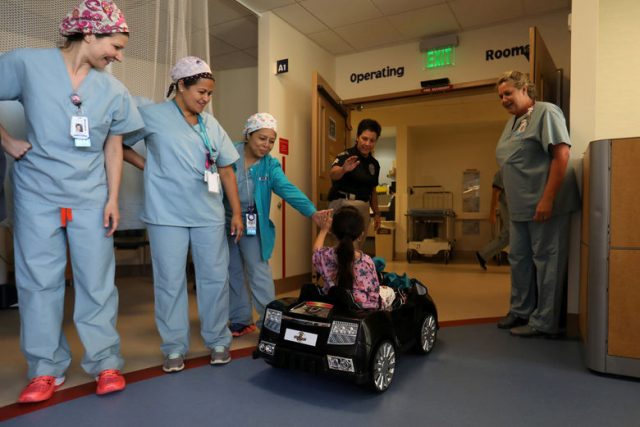 Andrea Destraio, 5, slaps hands with medical staff and invited police officers whose charity donated to Rady Children's Hospital to start a program that uses remote control cars to take young patients to the operating room, in San Diego, California, U.S. September 19, 2017.     REUTERS/Mike Blake     TPX IMAGES OF THE DAY