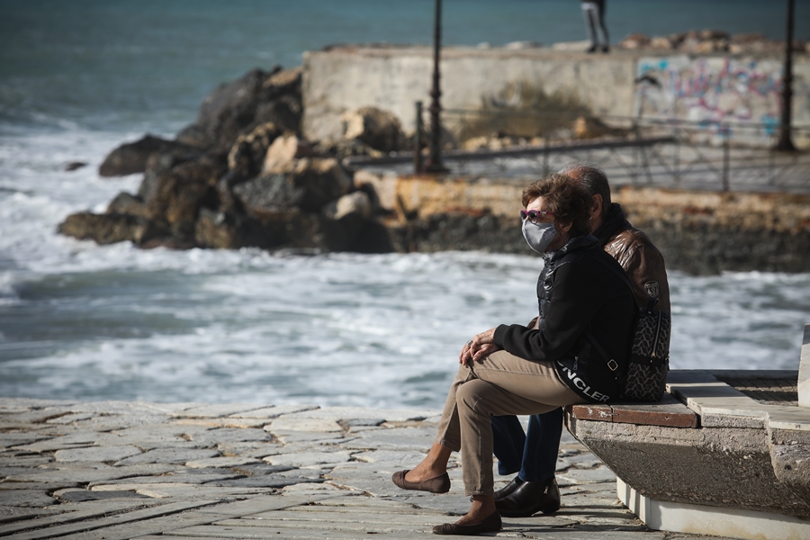 Ζευγάρι με μάσκα κάθονται σε παγκάκι