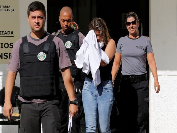 Francoise Souza Oliveira, 40, wife of Greek Ambassador for Brazil Kyriakos Amiridis, is escorted by police officers as she is transferred from the police station to a jail in Belford Roxo
