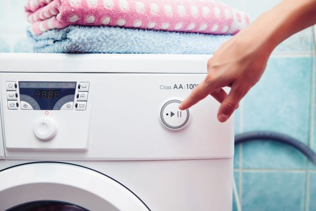 37392999 - the washing machine which costs in a bathroom. the woman operates the washing machine