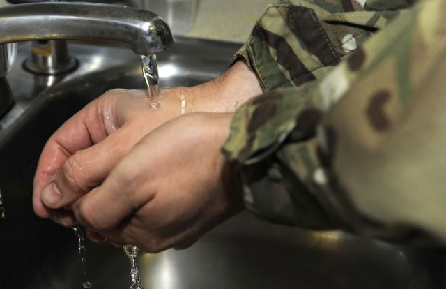 A soldier is pictured washing his hands.