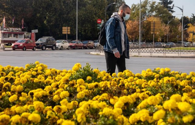 αγόρι με μάσκα περπατά πίσω από κίτρινα λουλούδια