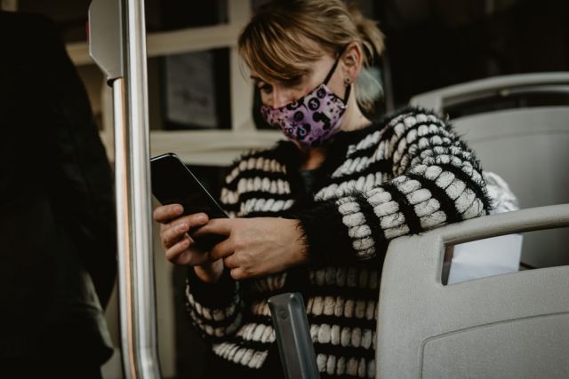 Κοπέλα με μάσκα και κινητό στο μετρό