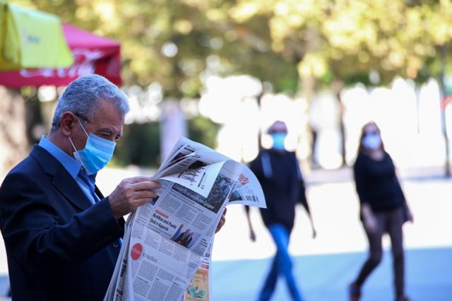 Άνδρας με μάσκα διαβάζει εφημερίδα
