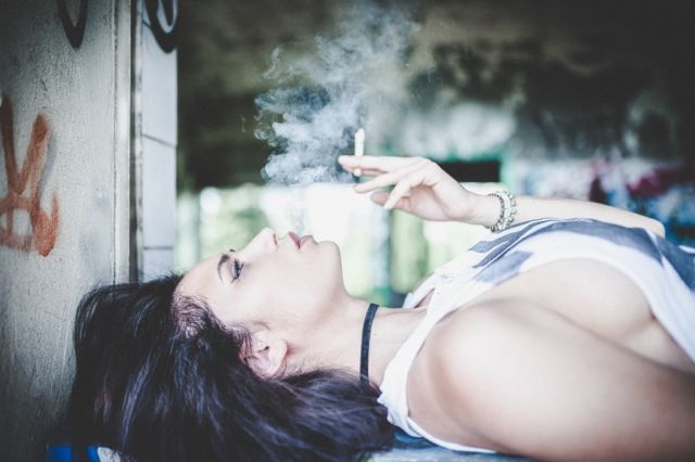 Γυναίκα ξαπλωμένη κάνει τσιγάρο 