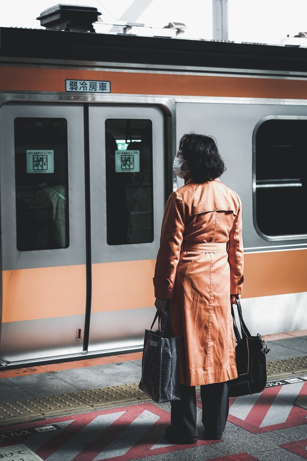 Γυναίκα με μάσκα περιμένει το τρένο 