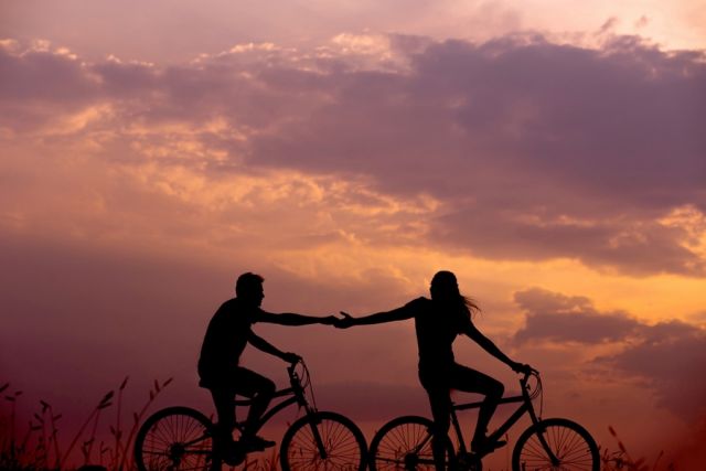 ζευγάρι κάνει ποδήλατο και πιάνονται από το χέρι