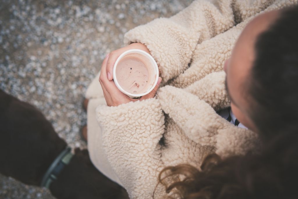 Κοπέλα με γούνα κρατάει ζεστό καφέ