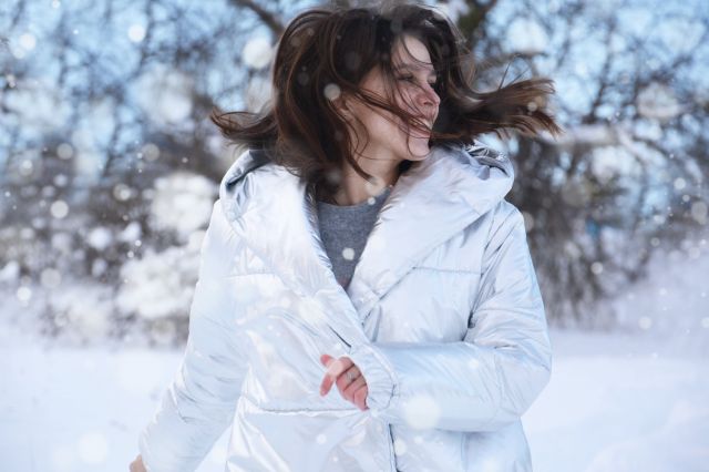 Γυναίκα στο χιόνι με λευκό μπουφάν 